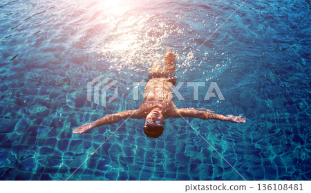 Young athletic man swimming in the swimming pool 136108481