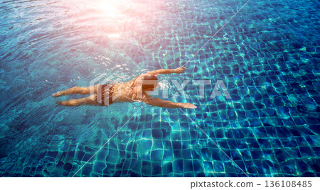 Young athletic man swimming in the swimming pool 136108485