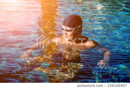 Young athletic man swimming in the swimming pool 136108487