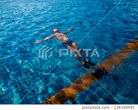 Young athletic man swimming in the swimming pool 136108495