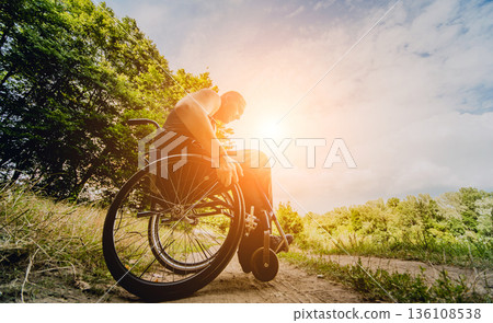 Disabled man resting in a campsite with friends. Wheelchair in the forest Disabled man resting in a campsite with friends. Wheelchair in the forest 136108538