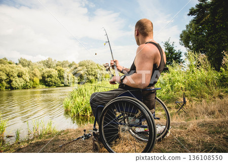 Handicapped man fishing at a lake. Wheelchair camping. Handicapped man fishing at a lake. Wheelchair camping. 136108550