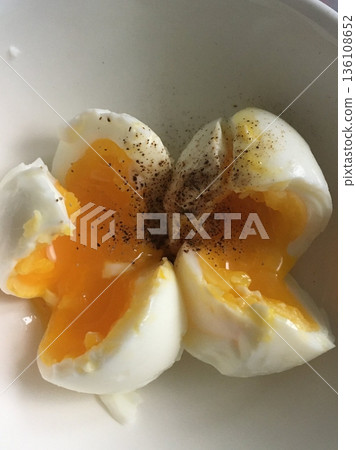 Boiled egg with smooth white exterior and firm yellow yolk inside, showcasing its simple appearance and versatile use as a nutritious and classic food item 136108652
