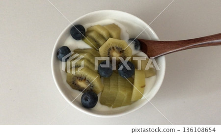 Greek yogurt served in a bowl topped with fresh colorful fruits, showcasing creamy smooth texture, vibrant natural colors, and refreshing wholesome appearance in close-up detail 136108654