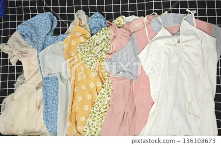 Clothes hanging neatly on hangers under the sun, gently swaying in the breeze—offering a perfect glimpse of fresh laundry days, clean fabric, and simple everyday beauty in every scene. 136108673