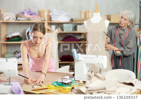 Woman tailor drawing a sketch of clothes on brown paper Woman tailor drawing a sketch of clothes on brown paper 136109337