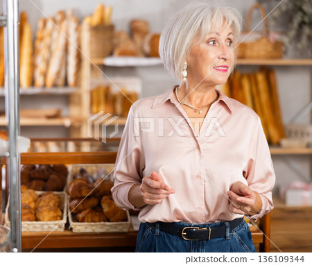 Mature female customer choosing bread and other delicious pastries in bakery Mature female customer choosing bread and other delicious pastries in bakery 136109344