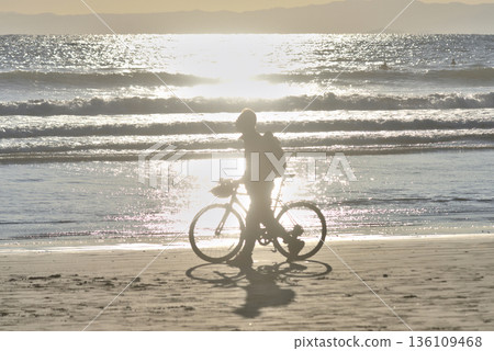 A man pulling a bicycle on the sandy beach of Katase Nishihama in the evening A man pulling a bicycle on the sandy beach of Katase Nishihama in the evening 136109468