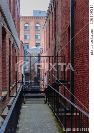 Narrow alley between two brick buildings with old fashion windows. 136109515