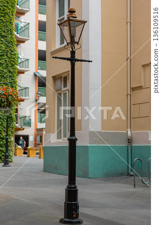 Vintage Victorian era iron street lamp in the background of buildings of the city. Vintage Victorian era iron street lamp in the background of buildings of the city. 136109516