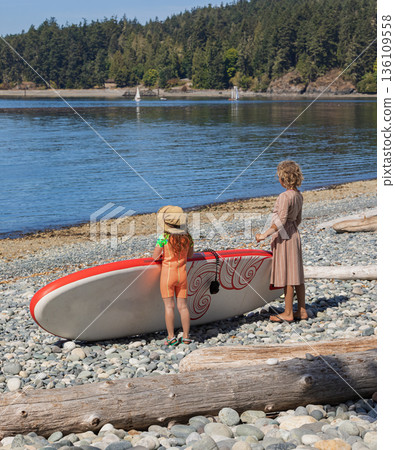 Two kids girls with the sup board on the shore preparing for an activity in the sea. Summer vacation Two kids girls with the sup board on the shore preparing for an activity in the sea. Summer vacation 136109558