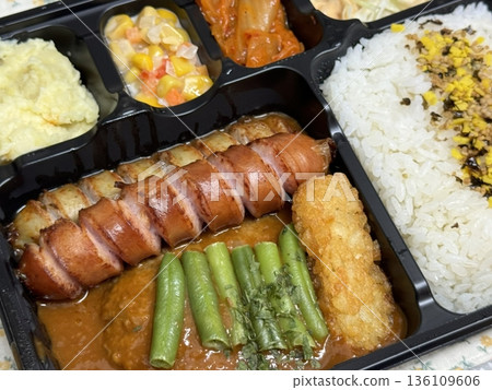 Bento or dosirak box filled with rice, assorted side dishes, vegetables, and protein like meat or fish, all neatly arranged to create a balanced, colorful, and visually appealing meal 136109606
