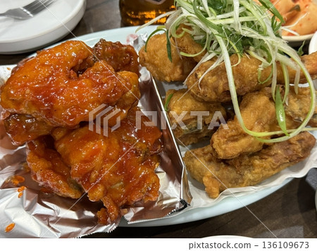 Crispy Korean fried chicken, perfectly glazed with a sweet and spicy sauce. Ideal for food photography and menus, showcasing the irresistible crunch and flavor of this beloved dish. 136109673