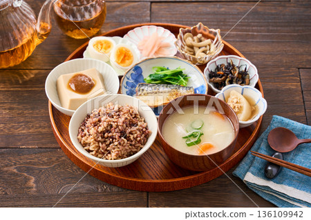 A Japanese breakfast with small dishes: mixed grain rice, miso soup, and grilled salted mackerel A Japanese breakfast with small dishes: mixed grain rice, miso soup, and grilled salted mackerel 136109942