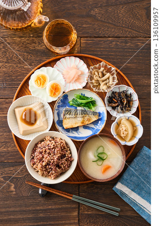 A Japanese breakfast with small dishes: mixed grain rice, miso soup, and grilled salted mackerel 136109957