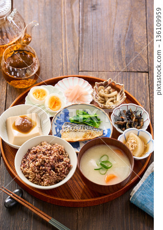 A Japanese breakfast with small dishes: mixed grain rice, miso soup, and grilled salted mackerel A Japanese breakfast with small dishes: mixed grain rice, miso soup, and grilled salted mackerel 136109959