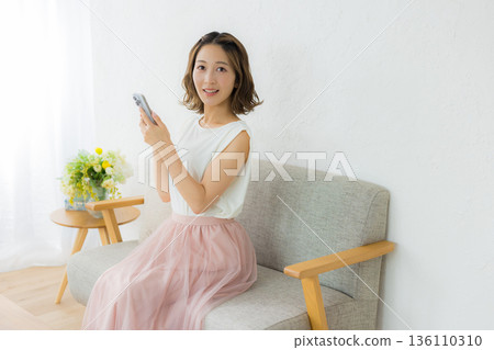 A smiling woman looking at a smartphone A smiling woman looking at a smartphone 136110310