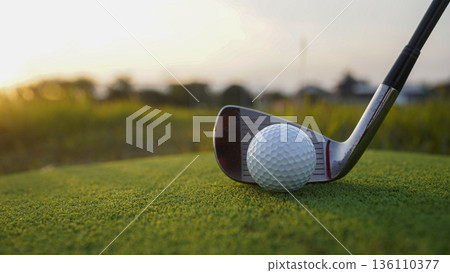 Golf clubs and balls on a green lawn in a beautiful golf course with morning sunshine. 136110377