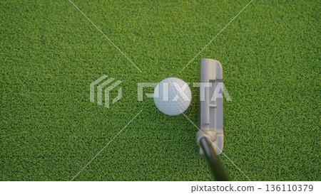 Golf clubs and balls on a green lawn in a beautiful golf course with morning sunshine. 136110379