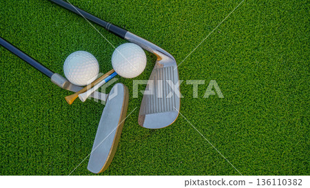 Golf club and golf balls on a green lawn in a beautiful golf course with morning sunshine. 136110382