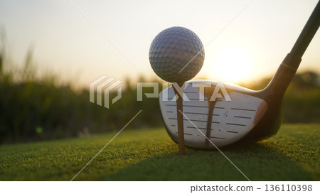 Golf clubs and balls on a green lawn in a beautiful golf course with morning sunshine. 136110398