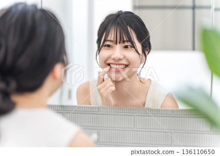 Young Asian woman checking her teeth alignment in the bathroom mirror (dental care, whitening, orthodontics) Young Asian woman checking her teeth alignment in the bathroom mirror (dental care, whitening, orthodontics) 136110650