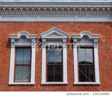 Details of three arched windows in classic style on a brick wall of the house 136110969