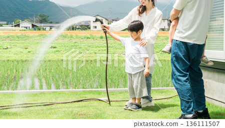 男孩和家人在花園裡澆草坪,家庭(房子、花園、室外) 男孩和家人在花園裡澆草坪,家庭(房子、花園、室外) 136111507