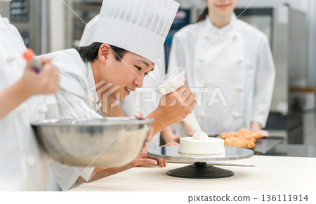 Pastry chefs, cake makers, and pastry artisans making cakes and pastries in the kitchen 136111914