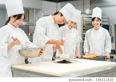 Pastry chefs, cake makers, and pastry artisans making cakes and pastries in the kitchen 136111916