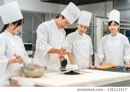 Pastry chefs, cake makers, and pastry artisans making cakes and pastries in the kitchen 136111917