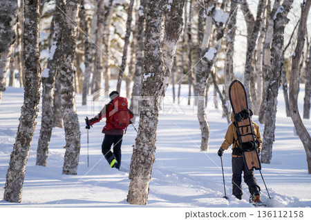 A realistic winter mountain outdoor scene portrayed by backcountry climbers and snowboarders navigating the snowy forests of eastern Hokkaido A realistic winter mountain outdoor scene portrayed by backcountry climbers and snowboarders navigating the snowy forests of eastern Hokkaido 136112158