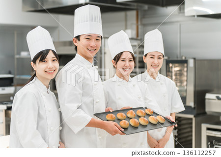 Chefs and cooks in chef coats standing in the kitchen 136112257