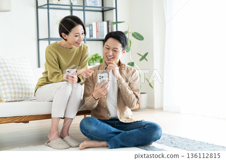 A middle-aged couple watching a smartphone in the living room A middle-aged couple watching a smartphone in the living room 136112815