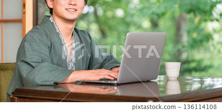 A man in a yukata working on a computer in a room at a hot spring inn A man in a yukata working on a computer in a room at a hot spring inn 136114108