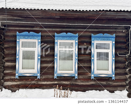 traditional Russian log cabin with carved architraves in winter in the village 136114437