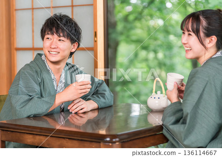 一對穿著浴衣的夫婦在日式旅館的花園景觀房間喝茶 一對穿著浴衣的夫婦在日式旅館的花園景觀房間喝茶 136114667