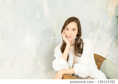 Long-haired woman sitting on a chair Long-haired woman sitting on a chair 136114782