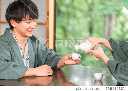 穿著浴衣的男女在日式旅館的房間裡端著飲料,已婚夫婦,情侶 穿著浴衣的男女在日式旅館的房間裡端著飲料,已婚夫婦,情侶 136114881