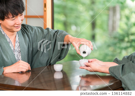 穿著浴衣的男女在日式旅館的房間裡端著飲料，已婚夫婦，情侶 136114882