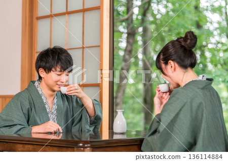 Men and women in yukatas pouring sake in a Japanese-style room at a ryokan, married couple, couple (sake) Men and women in yukatas pouring sake in a Japanese-style room at a ryokan, married couple, couple (sake) 136114884