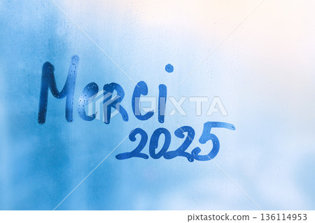 Handwritten lettering thanks in French Merci and arabic numerals 2025 on misted glass on blue window 136114953