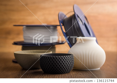 Plastic filament for 3D printer and printed products on wooden table. 136115744