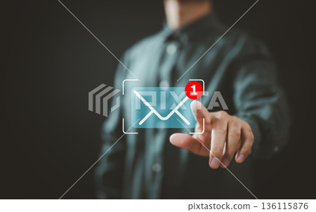 Businessman interacting with virtual email notification symbol and new message alert Businessman interacting with virtual email notification symbol and new message alert 136115876