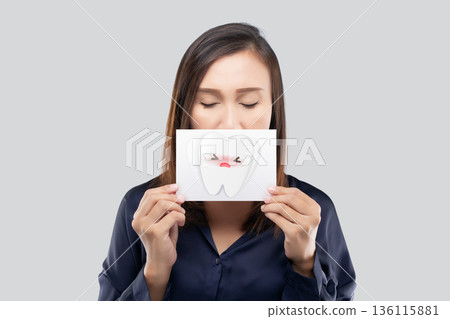 Woman holding cartoon tooth card illustrating loose tooth and dental pain concept 136115881