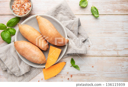 Raw sweet potatoes on plate, preparing healthy meal 136115939
