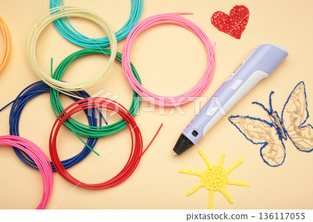 Children's 3D handle with plastic coils red, white, yellow, blue on beige background. Plastic PLA and ABS filament material for printing on a 3D pen 136117055