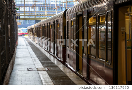 Berlin, germany, august 11, 2023. S-bahn train waits at a berlin platform with another train in the distance, urban transit scene highlighting modern rail infrastructure Berlin, germany, august 11, 2023. S-bahn train waits at a berlin platform with another train in the distance, urban transit scene highlighting modern rail infrastructure 136117930