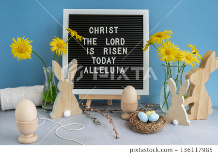 Letter board with message CHRIST THE LORD IS RISEN TODAY ALLELUIA on festive blue background and eco-friendly zero waste natural decoration. Yellow daisies flowers. Bunny egg. Holiday greeting Letter board with message CHRIST THE LORD IS RISEN TODAY ALLELUIA on festive blue background and eco-friendly zero waste natural decoration. Yellow daisies flowers. Bunny egg. Holiday greeting 136117985