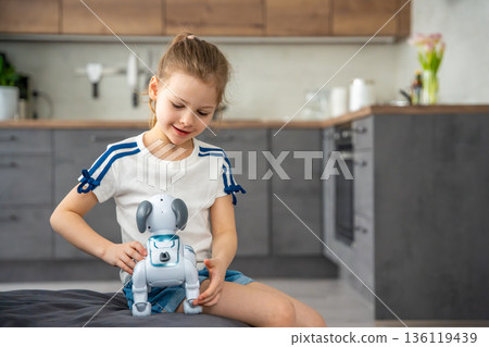 Child playing and interacting with robotic dog on sofa at home. Human robot interaction and digital companionship in modern childhood. Child playing and interacting with robotic dog on sofa at home. Human robot interaction and digital companionship in modern childhood. 136119439